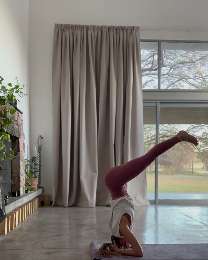 Noel en una postura invertida de yoga en un salón luminoso